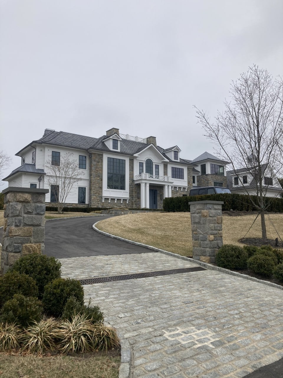 Completed residential facade with dark-framed windows, white siding, and stone